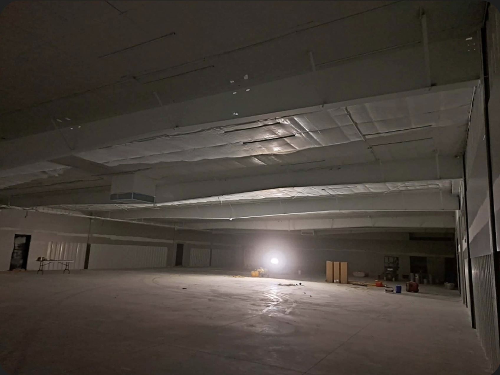 Dark unfinished Dollar General interior with raw deck and duct work