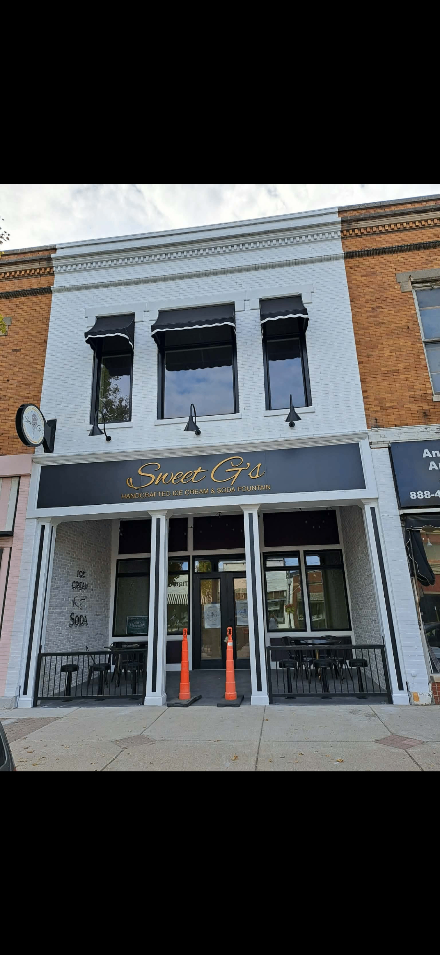 Sweet G's storefront painted white with black awnings and gold signage in downtown Bristol, Indiana