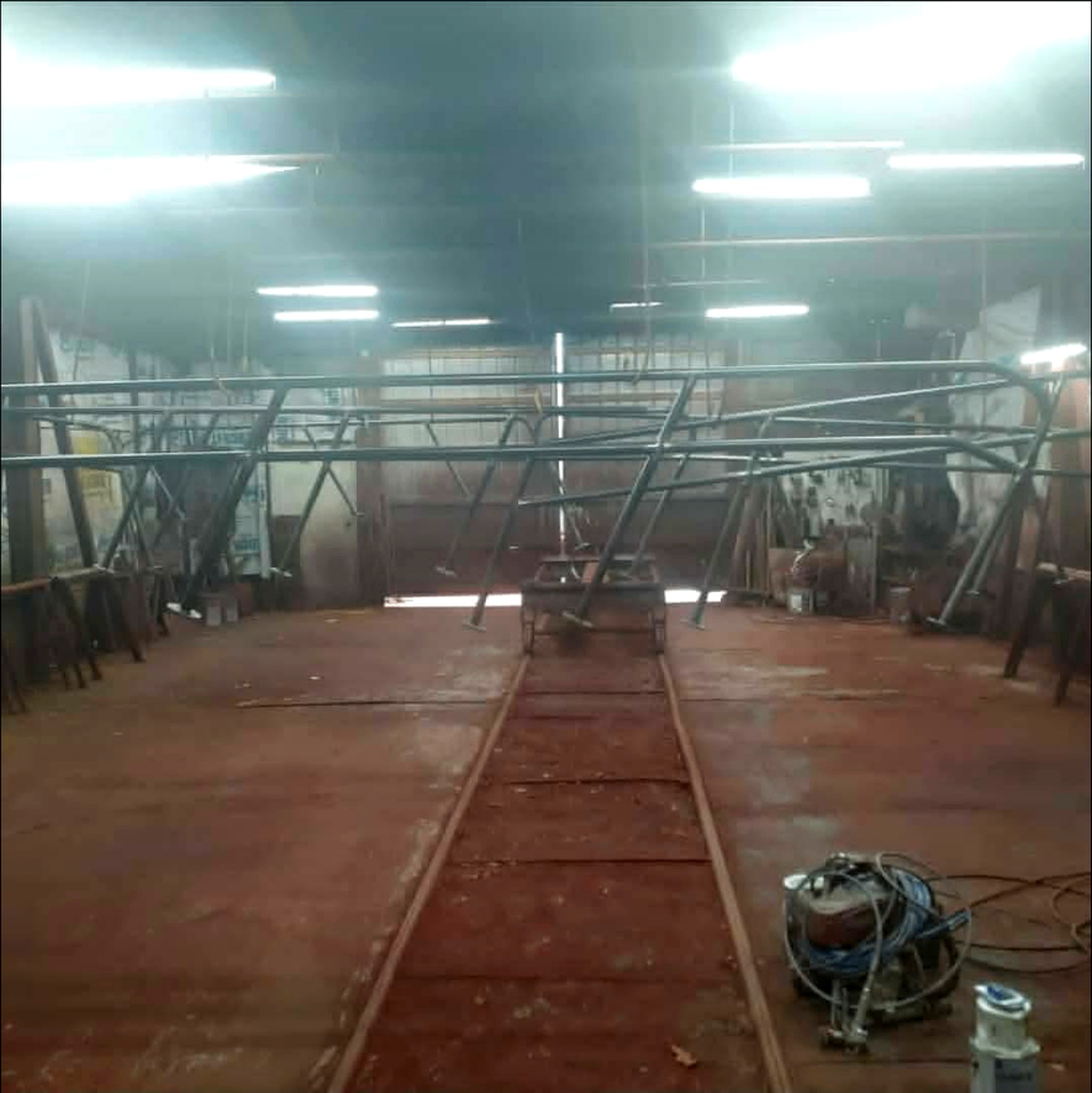 Bare steel hand rail sections hung across the paint shop before coating