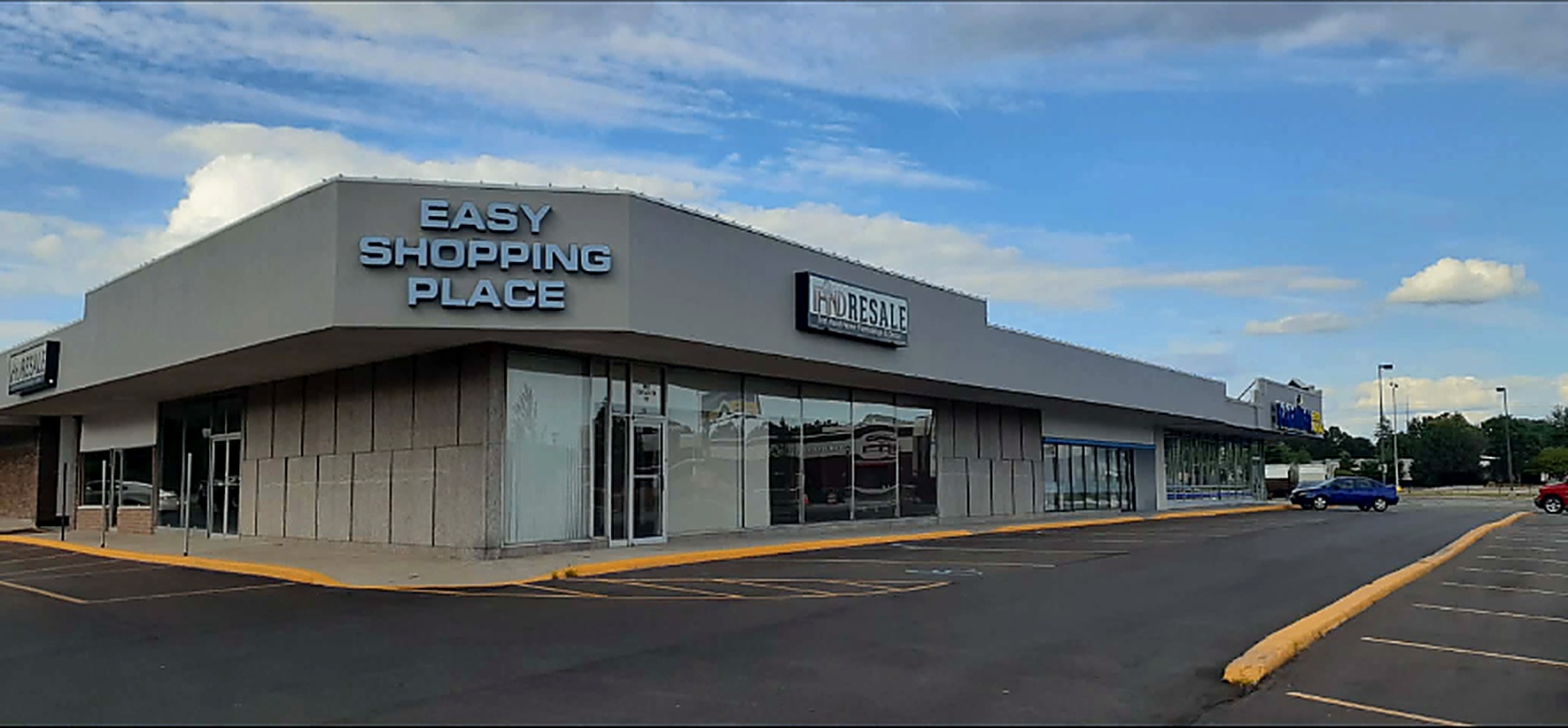 Easy Shopping Place strip mall with a faded gray exterior before painting