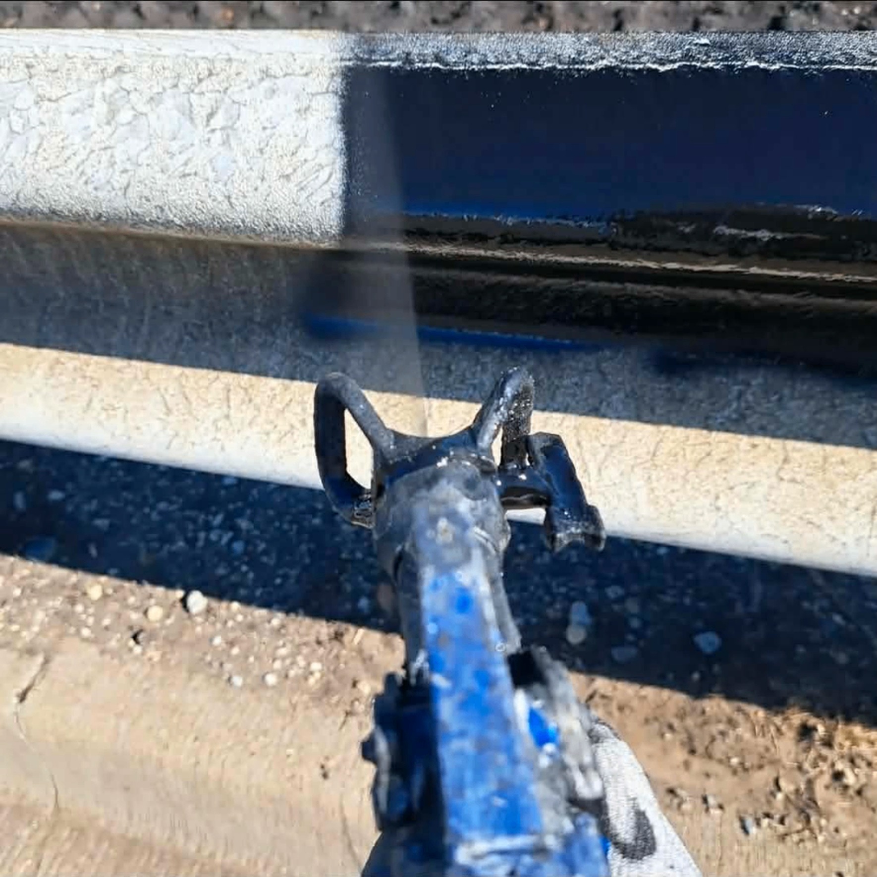 Faded, chalky bridge guard rail mid-spray on Cassopolis Street